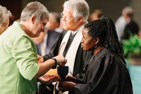 The Rev. Tonya Elmore, pastor at Enterprise First United Methodist Church, takes communion from the Rev. Virginia Kagoro, pastor at Locust Bluff United Methodist Church, at the 2015 Alabama-West Florida Annual Conference. Photo by Luke Lucas, Alabama-West Florida.