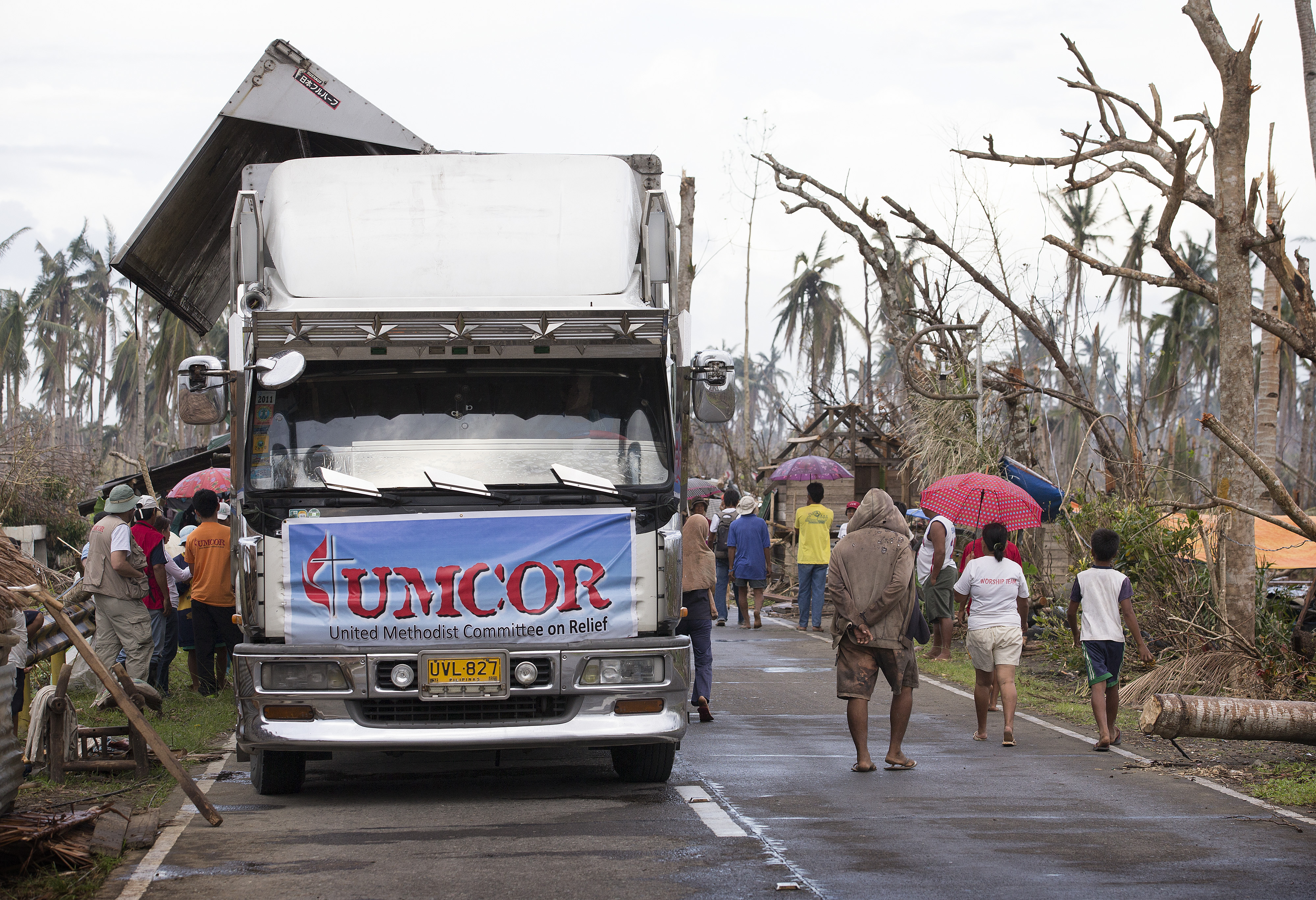Community members walk past a food distribution site for the United Methodist Committee on Relief following Typhoon Haiyan in Dagami, Philippines. Photo by Mike DuBose, UM News.