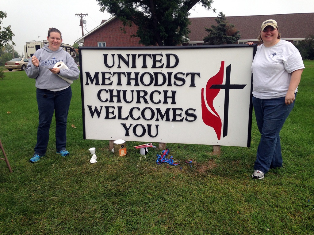 The Rev. Andrea Beyer (left) and the Rev. Cathryn Love stand near a church sign in Beaver Crossing, Nebraska. Image courtesy of Great Plains Conference/creative commons. 