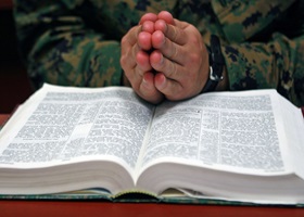 Praying hands over a Bible.