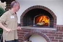 Gil Kruger, a member of Hamline Church United Methodist in St. Paul, Minnesota, bakes a pizza in the congregation's new outdoor oven. Video image by United Methodist Communications.