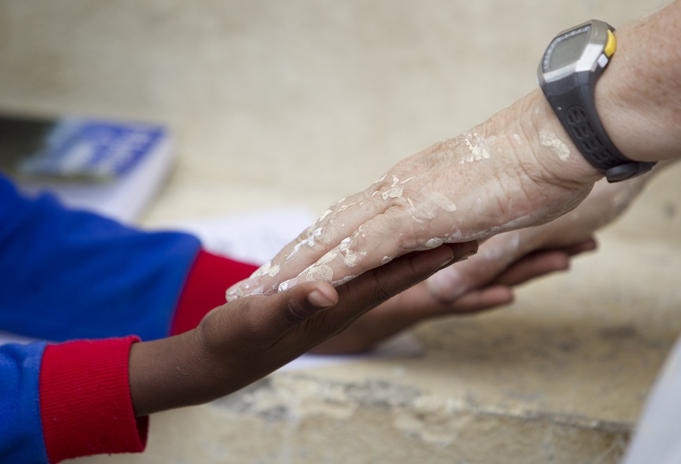 Her hands spattered with paint, volunteer Kathy Ahmad (right) plays a game with Franckenson Renevil during a break from renovating the Methodist Children's Home orphanage in Port-au-Prince, Haiti, in 2010. Photo by Mike DuBose, United Methodist News Service.