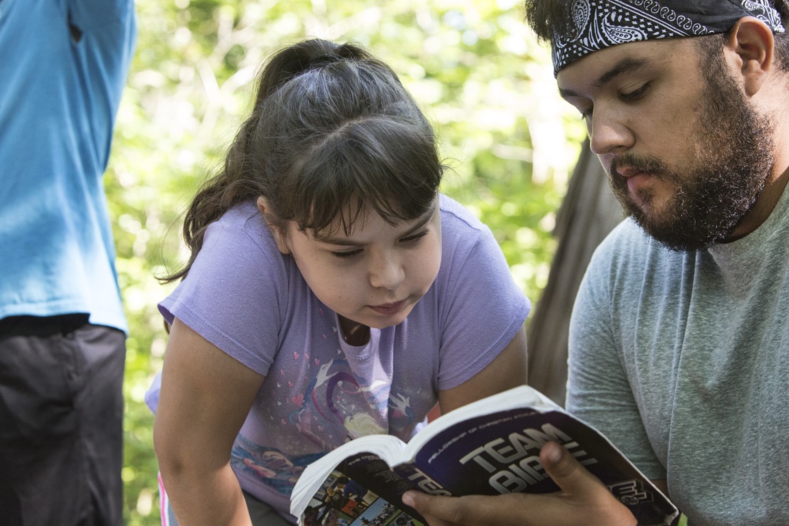Camper Klaira Hargrove studies the Bible with counselor Emilio Almendarez during morning worship at Cedar Crest Camp in Lyles, Tennessee.