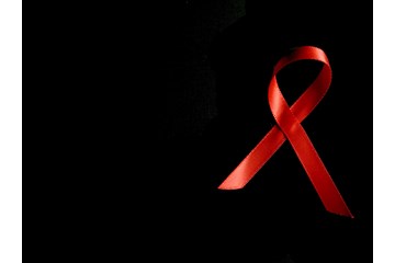 AIDS ribbon is seen on solid black background. Courtesy of pexels.com. 