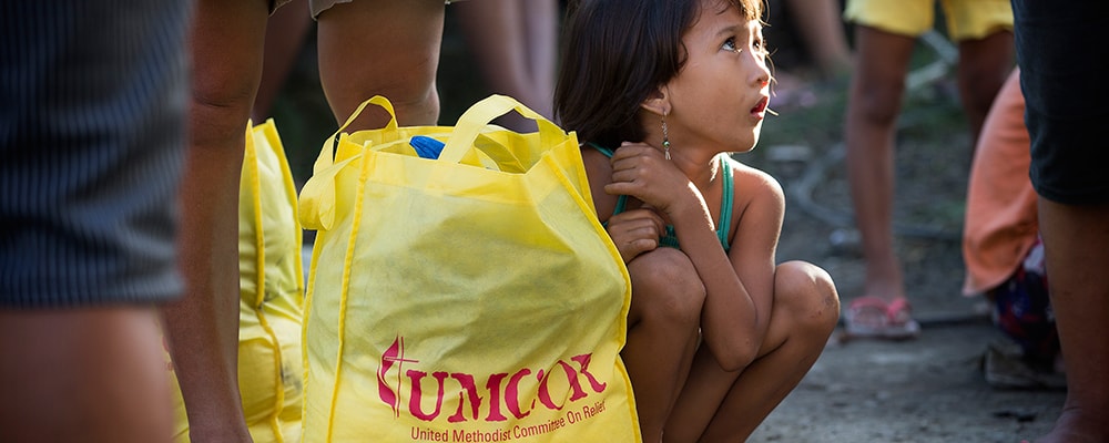 Donna-Grace Orbong, 5, sits with her family's food bag following a distribution by the United Methodist Committee on Relief for survivors of Typhoon Haiyan in Tacloban, Philippines.