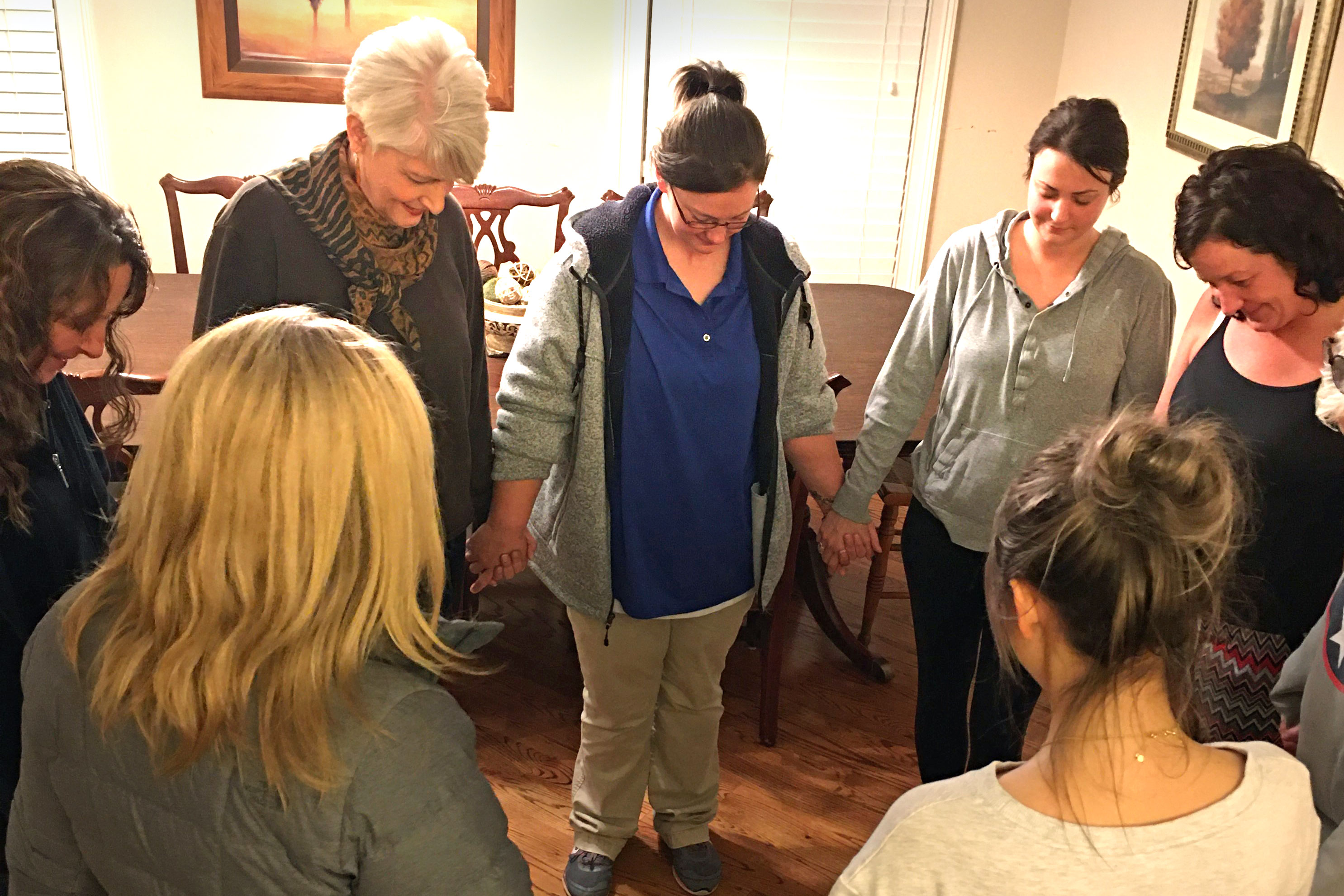 Volunteer Pat Ralls (top, left) leads the Healing Housing residents in prayer. Photo courtesy of Healing Housing.