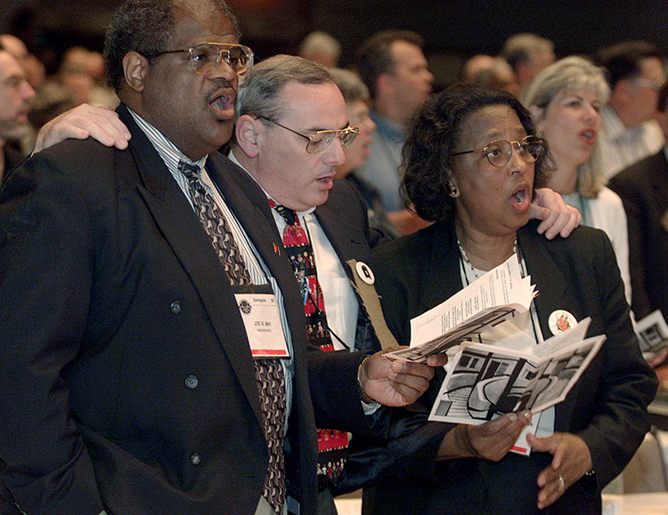 Mississippi Conference delegates (from left) Joe W. May, Larry M. Goodpaster and Dora S. Washington sing together during a service of repentance for racism within The United Methodist Church during 2000 General Conference in Cleveland. File photo by Mike DuBose, UM News.