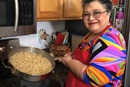 Bilha Alegria holds up a pan of Mexican rice she has just cooked