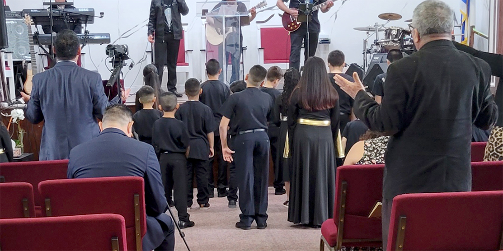 Today, Miguel and Maria and their family participate in a new church in the U.S. where Miguel provides worship music leadership. They are shown from the back to protect their identities. Photo: Courtesy NY JFON