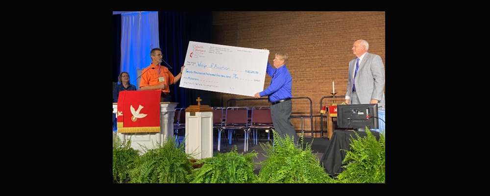 On Monday morning, June 6, Rev. Garth Duke-Barton, pictured above in blue, presented a check to the Kamina Orphanage and the Wings of the Morning Aviation ministry of the North Katanga Conference. Receiving the check on the behalf of Global Ministries were Jim and Bernice Keech, SEJ mission advocates. 