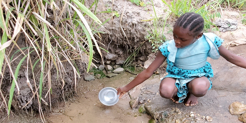 A young girl patiently collects water for her family from a slow-running spring. Collecting water from the source and treating it with chlorine tablets decreases the spread of cholera and other waterborne diseases. Photo: Courtesy of North Katanga UMC Health Board.