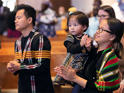 Nadi Nadi (left) and July Ling join in worship with their daughter, Eunice, 2, during a Festival of Nations celebration of World Communion Sunday at Hillcrest United Methodist Church in Nashville, Tenn. The family is part of the El Shaddai congregation that worships in Nepali. Photo by Mike DuBose, UM News.