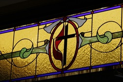 A stained glass window depicts the Cross and Flame.