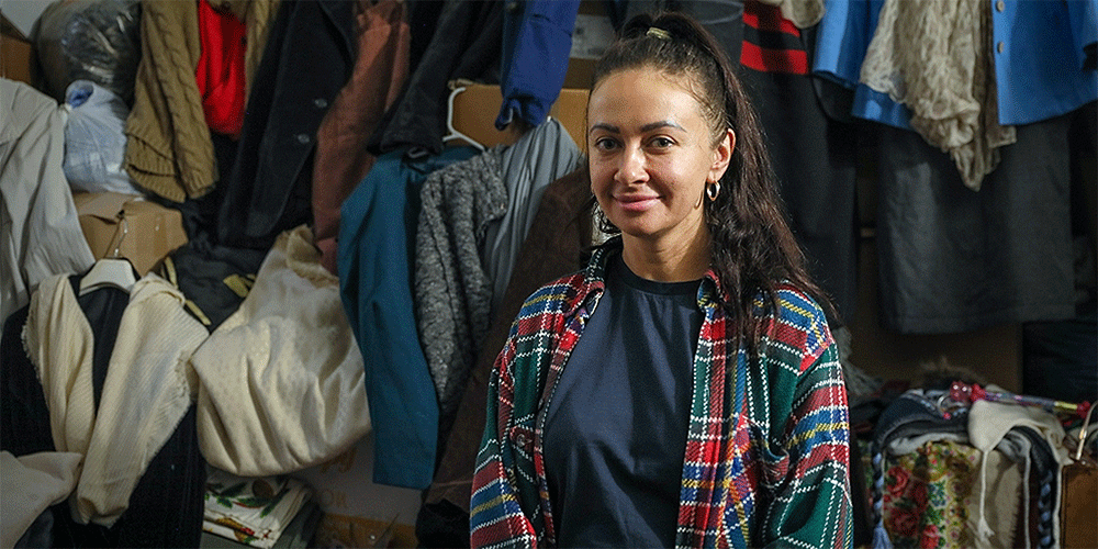 Natalia, a Ukrainian refugee, pauses as she sorts clothes at the CWS Balti Center in Moldova. She and her family have found “a warm hug” in this Moldovan community. Photo: Church World Service.