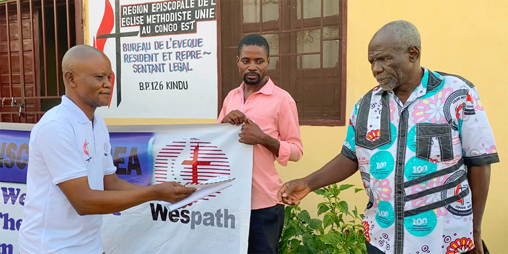 Pastor Kanya Kamahiro Georges (at right) receives his stipend during a presentation ceremony held at the Eastern Congo episcopal office. The assistance from Wespath allows 12 student pastors to buy food and provide for other needs for eight months. Photo by Chadrack Tambwe Londe, UM News.