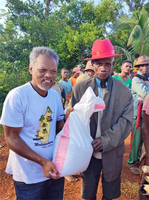 Bodo Abani Marielle (with red hat) receives foodstuff from Pastor Jean Aime Ratovohery of Ambodifasika United Methodist Church during a mission trip to Andranomavo, Madagascar. Church members distributed food to families affected by Cyclone Freddy, which devastated the region earlier this year. Photo by Justin Rakotoarimanana