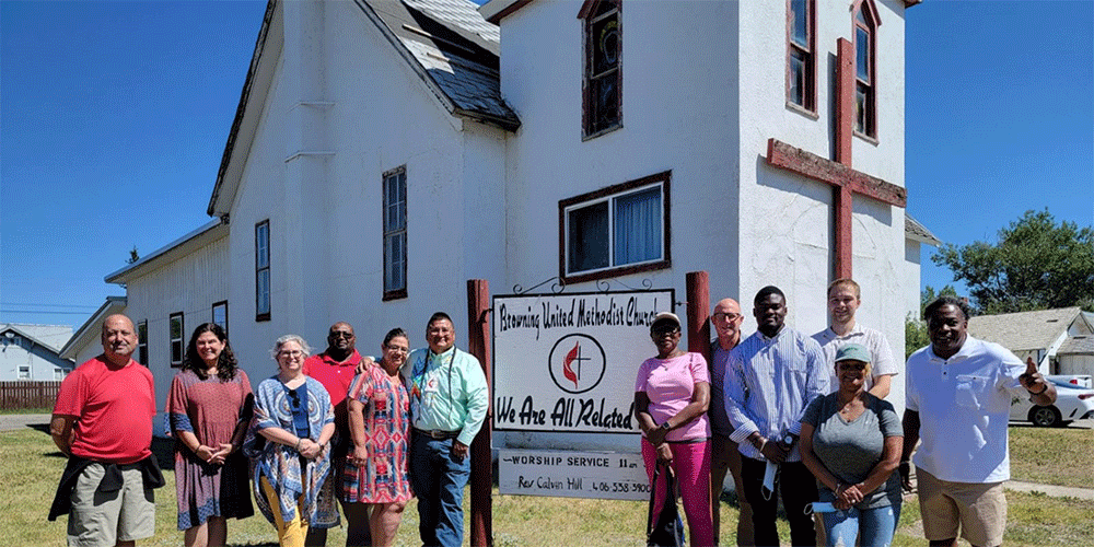 Terri Leone (2nd from left )and Drew classmates visit Rev. Calvin Hill (left of the church sign) at Browning UMC in Montana