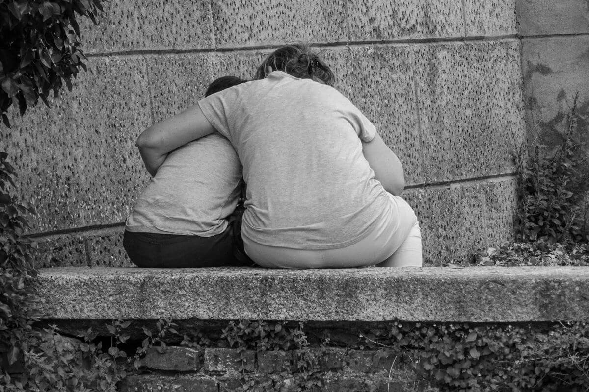 Adult hugging a child offering consolation.