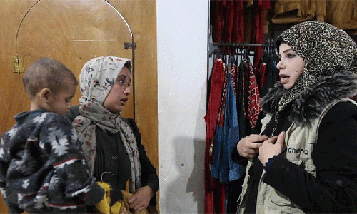 ANERA staff member assists a woman looking for winter clothes and a coat for her son. (Photo: Courtesy of ANERA)