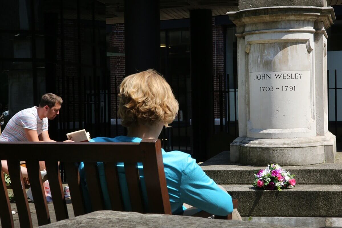 Peregrinos contemplativos sentados junto a la tumba de John Wesley, situada en un patio detrás de la Capilla Wesley en Londres. Foto de Kathleen Barry, Comunicaciones Metodistas Unidas.