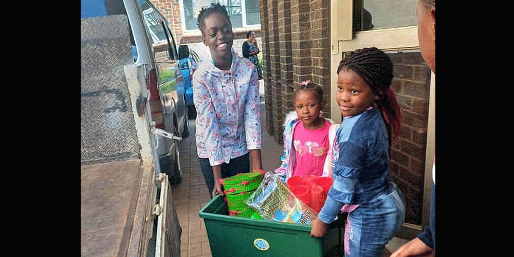 Maitaishe Gwara (from left) and Mecala and Chipiwa Zhungu carry their gifts to a vehicle for transportation to the local hospital in Harare, Zimbabwe. Members of the Harare Inner-City United Methodist Church junior Sunday school program raised $2,500 to provide gifts for children in the pediatric ward. Photo by Chenayi Kumuterera, UM News.