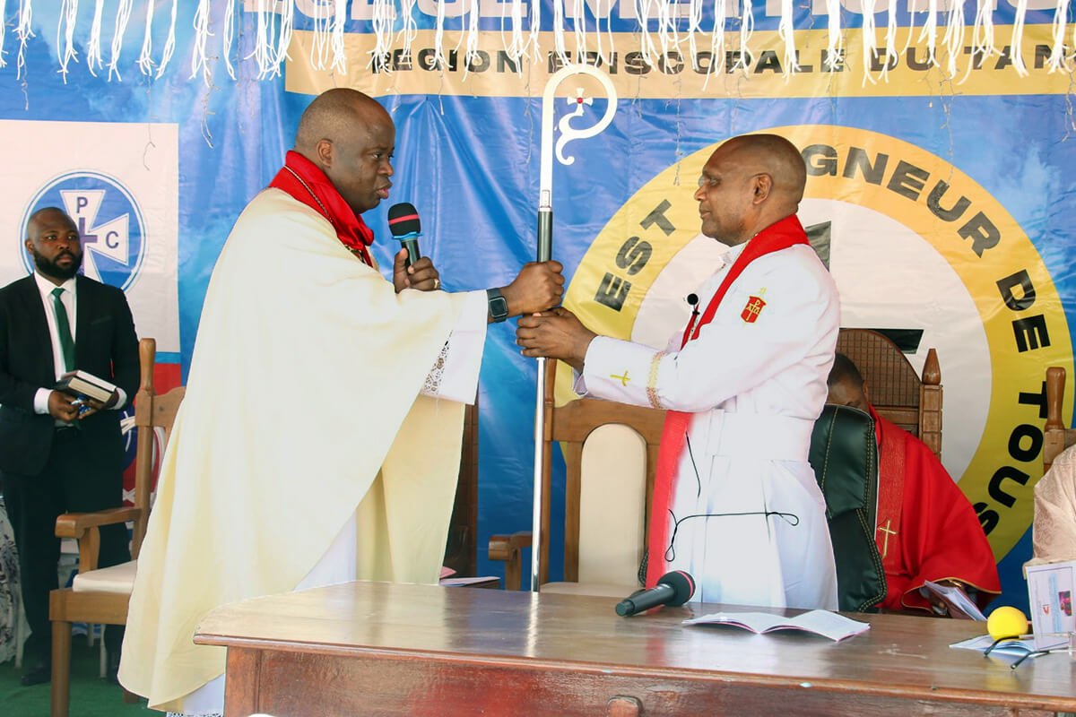 Bishop Mande Muyombo (left), president of the Africa Colleges of Bishops, presents the episcopal staff to Bishop Nelson Kalombo Ngoy during Ngoy’s installation as the first bishop of the new Tanganyika Episcopal Area on Sept. 14 in Kalemie, Congo. Photo by Chadrack Tambwe Londe, UM News.