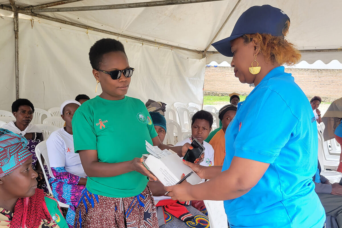 Janat Twahirwa, de Wiceceka, distribue des préservatifs aux participants lors d'un événement organisé à l'occasion de la Journée mondiale de lutte contre le sida, le 1er décembre, dans le secteur de Mukamira, dans le district de Nyabihu, au Rwanda. « Wiceceka » signifie « ne restez pas silencieux » en français. Au cours de cet événement, Janat Twahirwa s'est particulièrement attachée à fournir des préservatifs aux pairs éducateurs, afin qu'ils puissent les distribuer à leurs pairs dans le cadre des efforts continus de prévention du VIH. Photo de Samuel Iraguha Shema.