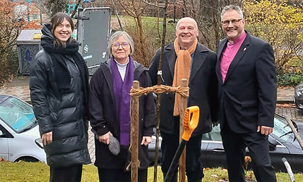 (From left) Pastor Rebekka Tibbe of the Evangelical Lutheran Church of St. Jürgen, the Rev. Gillian Horton-Krüger of Flensburg United Methodist Church and her husband, Peter Krüger, and United Methodist Bishop Werner Philipp pose for a photo after planting an apple tree at the St. Jürgen church, where the Flensburg congregation meets. Photo by Isabel Philipp.