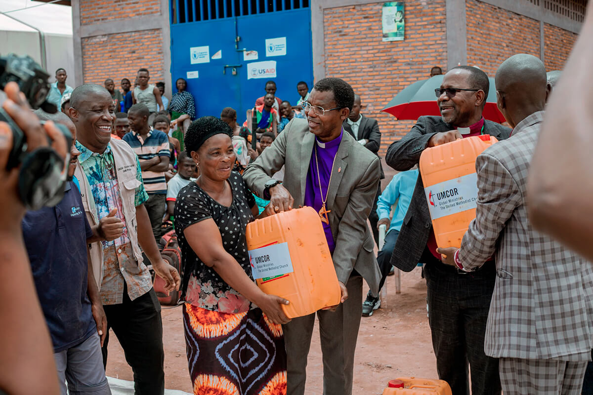 L’évêque João Sambo du Mozambique (à droite) et l’évêque Emmanuel Sinzohagera du Burundi (au centre) distribuent des bidons d’huile végétale au camp de Musenyi, au Burundi. Ils faisaient partie d’une délégation de l’Église méthodiste unie qui s’était rendue sur place en mars pour apporter un soutien matériel et spirituel aux réfugiés fuyant le conflit dans l’est du Congo. Le missionnaire international Abro Patrick se tient à gauche. Photo : Service de communication de la région épiscopale Burundi-Rwanda.