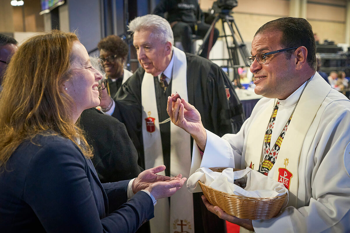L'évêque Héctor A. Burgos Núñez, qui préside les conférences d'Upper New York et de Susquehanna, distribue la communion aux participants lors du culte d'ouverture, le 23 avril 2024, à la Conférence Générale à Charlotte, en Caroline du Nord. À ses côtés, distribuant également la communion, se trouve l'évêque Rubén Saenz Jr. de la Conférence Horizon Texas, qui est désormais président du Conseil des évêques. Un organe de direction de l’Église Méthodiste Unie recommande que les États-Unis comptent 34 évêques à partir de 2028. Photo d’archive de Paul Jeffrey, UM News. 