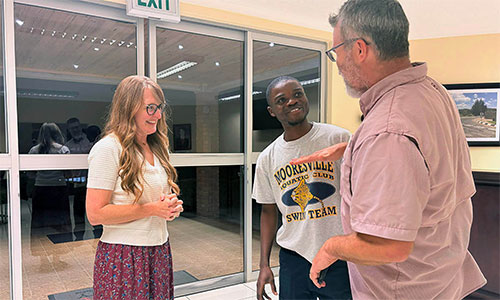 Mykal Jones (right) recalls how short Isaac Sakala (center) was when he and wife Traci Jones (left) last saw him 10 years before. The Joneses, who are from Dallas, Texas, supported Sakala’s education from primary school through his graduation at Africa University in Zimbabwe on June 6. Sakala is a beneficiary of the Excel Beyond program run by Family Legacy, a Zambian organization caring for orphans and disadvantaged children and youth. Photo by Eveline Chikwanah, UM News.