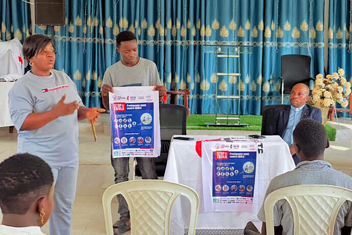 Judith Yanga Osongo (à gauche), Directrice de la communication de la Région Episcopale du Congo Est, sensibilise le public aux mesures de prévention contre Ebola dans une Eglise Méthodiste Unie de Beni, au Congo, au sein de la Conférence Annuelle du Kivu. Cette campagne de communication locale, soutenue conjointement par United Methodist Communications et Global Ministries, comprend la distribution d'affiches et de messages de prévention essentiels dans les zones touchées par l'épidémie du virus de Bundibugyo. Photo gracieusement fournie par la Région Episcopale du Congo Est.