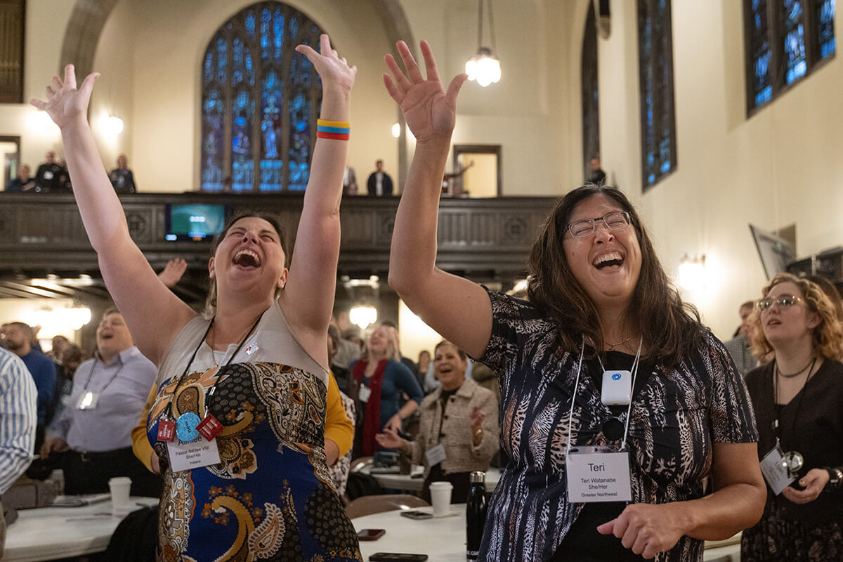Ashlee Vitz (a la izquierda) y Teri Watanabe levantan los brazos en alabanza durante el culto de apertura, el 21 de octubre, en el Encuentro de Liderazgo Metodista Unido, celebrado en la Iglesia Unida Knox, en Calgary, Canadá. El evento, que se extiende hasta el 24 de octubre, reúne a líderes laicos y clérigos de todo el mundo para imaginar un nuevo futuro para La Iglesia Metodista Unida. Foto de Mike DuBose, Noticias MU.